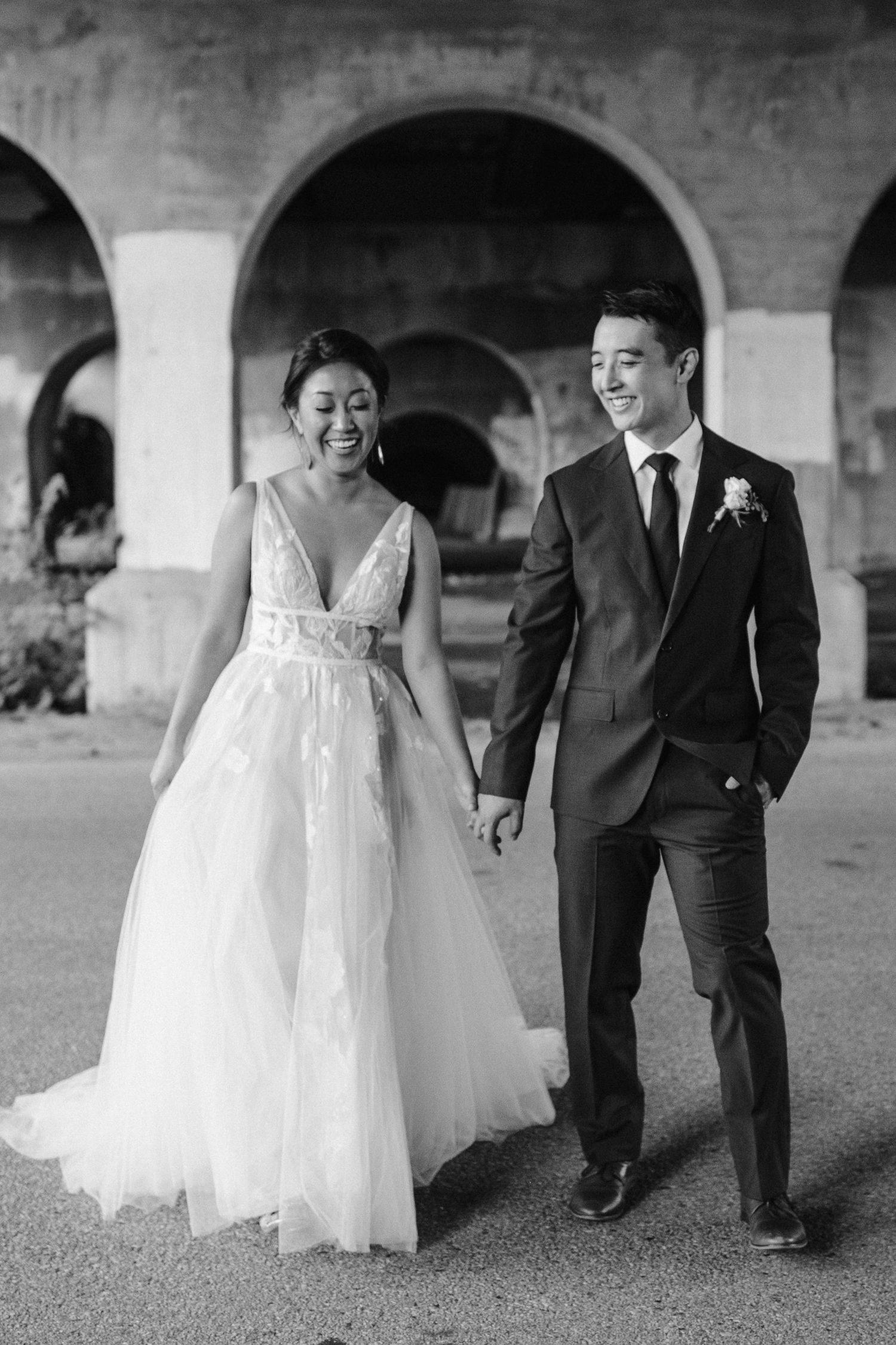 bride and groom walk together under bridge