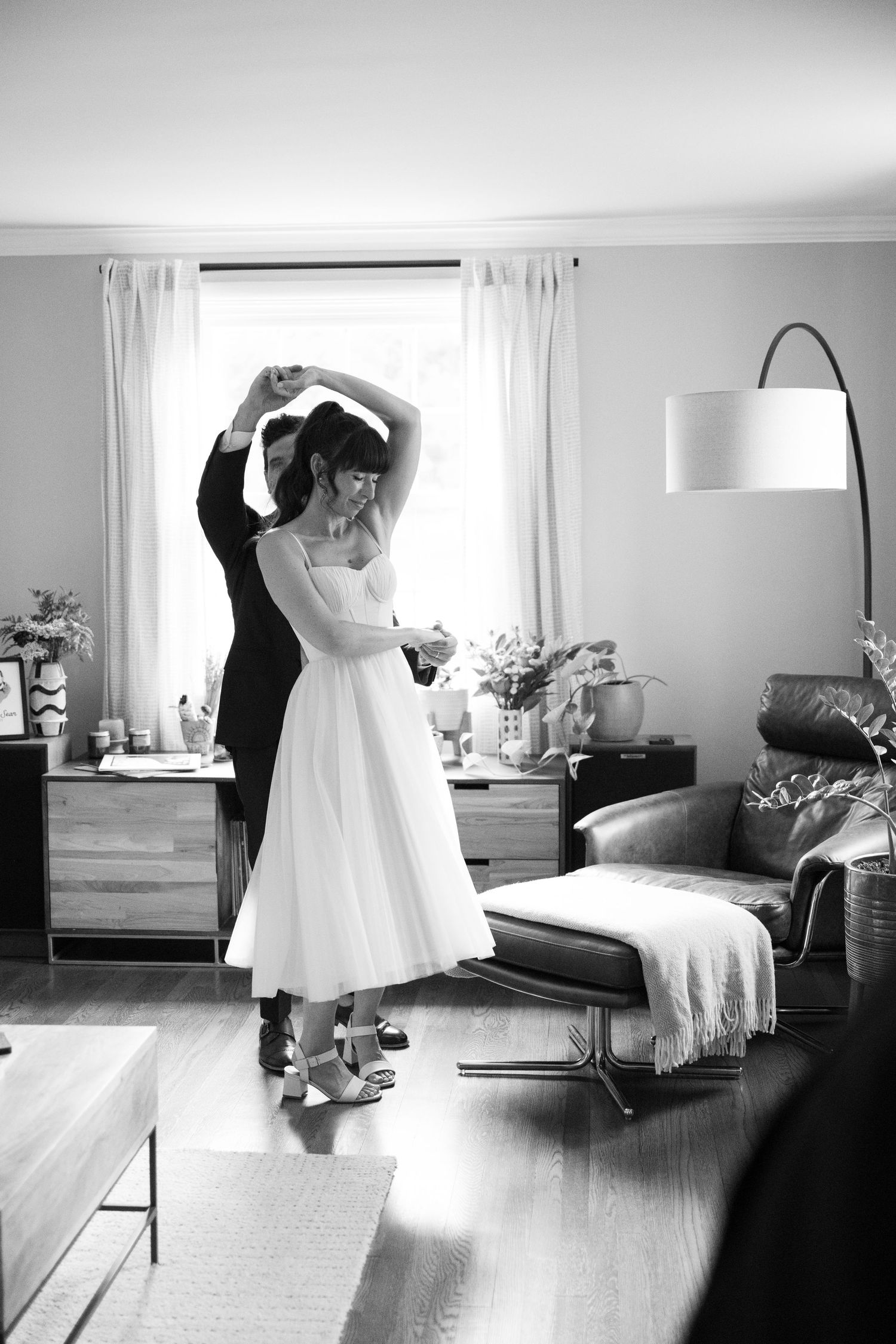 Black and white sequence showing bride getting dressed and fitted in wedding gown preparations.