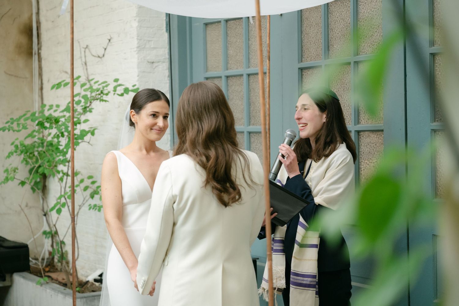 Small gathering in courtyard with greenery and vintage windows creating intimate atmosphere.