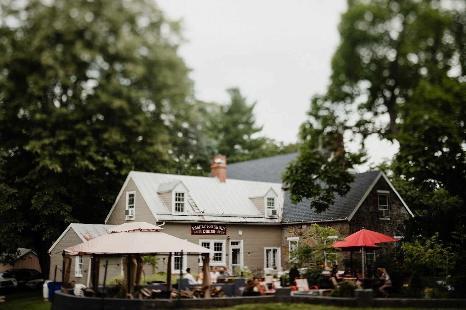 Charming white farmhouse with red umbrella and covered porch.