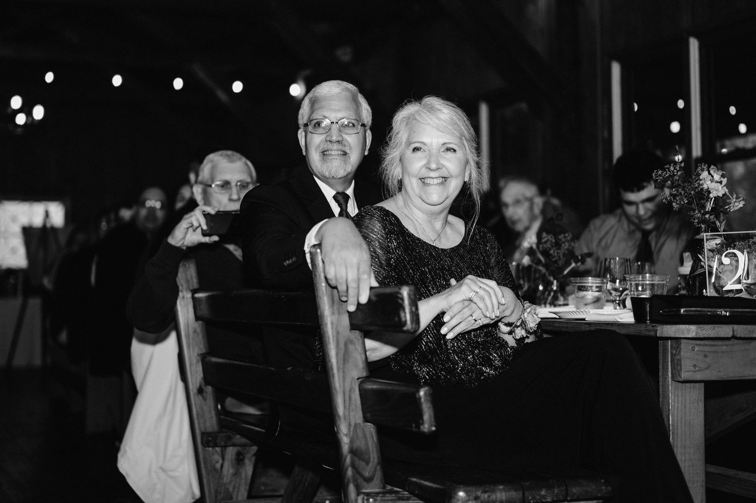Elegant wedding guests enjoying a candlelit reception dinner in black and white.