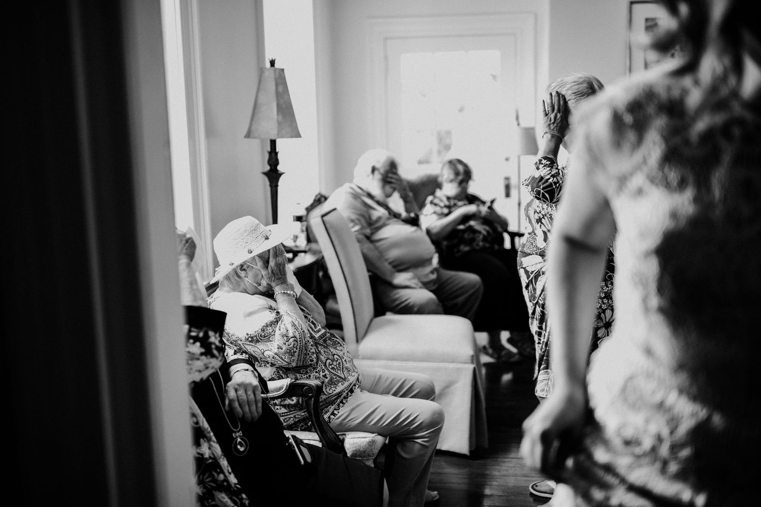 A black and white photo showing a group sitting together in a cozy room during a wedding day.