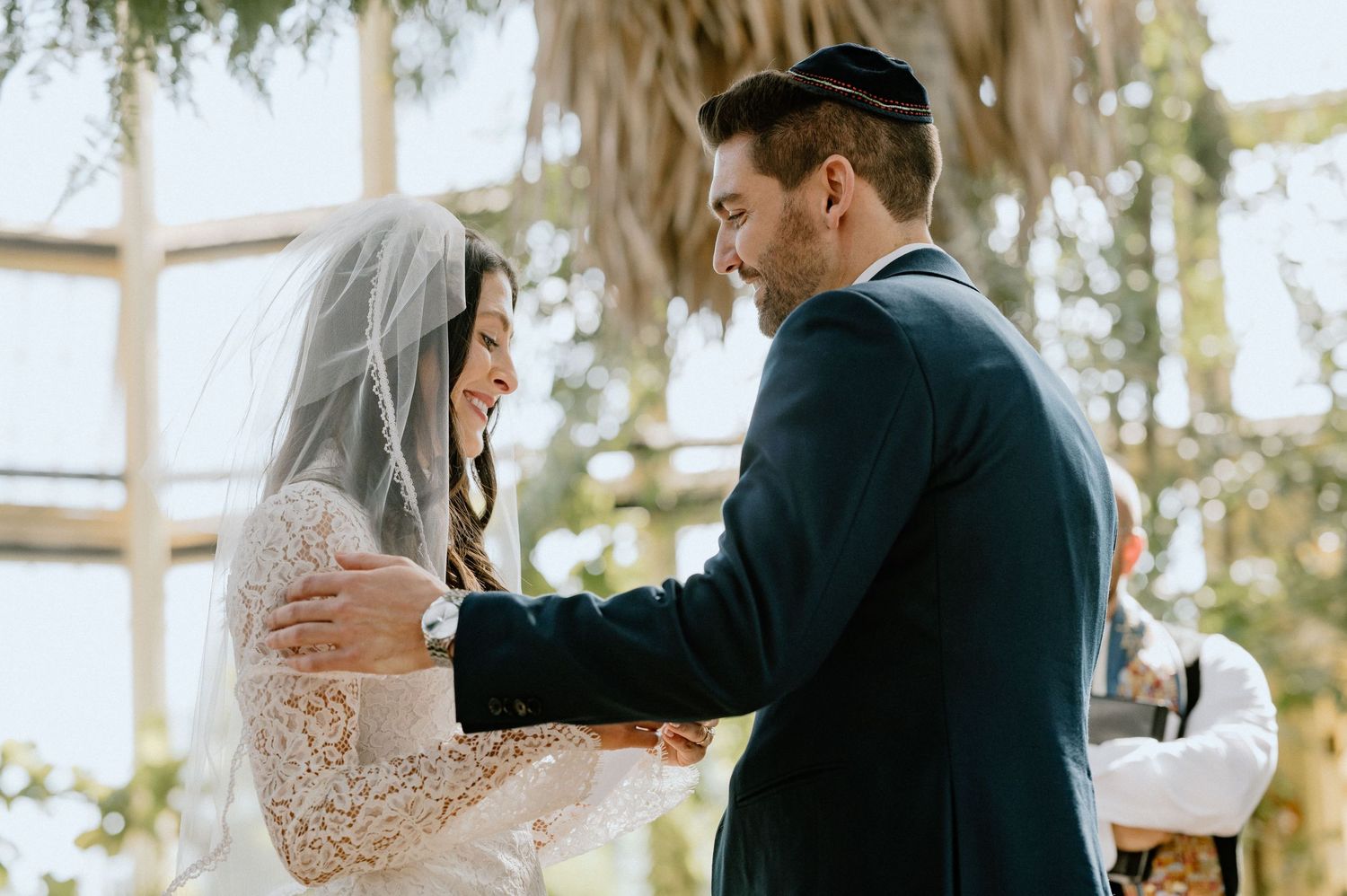A couple exchanges vows during an intimate greenhouse wedding ceremony surrounded by tropical plants.