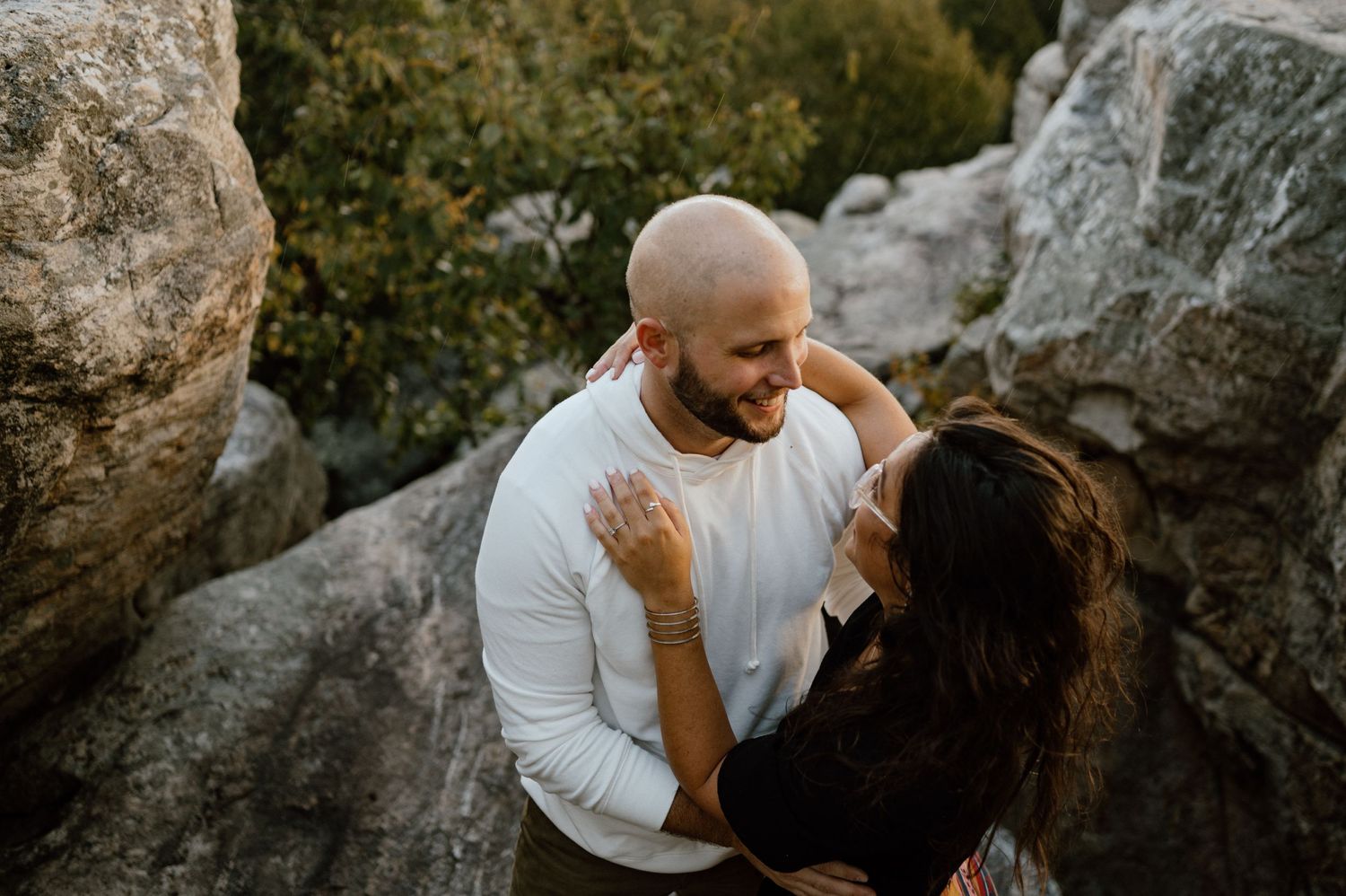 A couple shares a joyful moment while standing among rocky mountain outcrops.