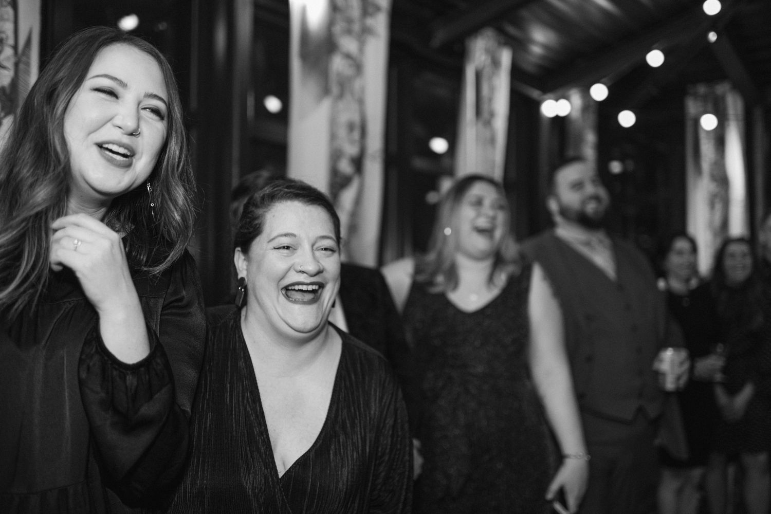 A candid moment of guests laughing during a wedding celebration.