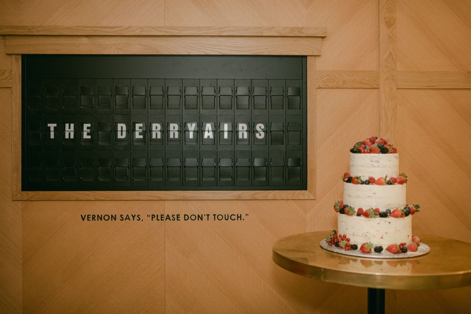 Wedding cake display next to 'The Berrystairs' signage in an elegant venue.