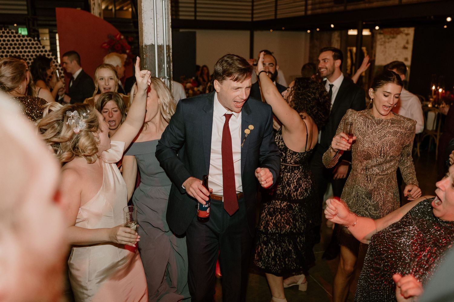 Wedding reception dance floor filled with guests dancing in formal attire.