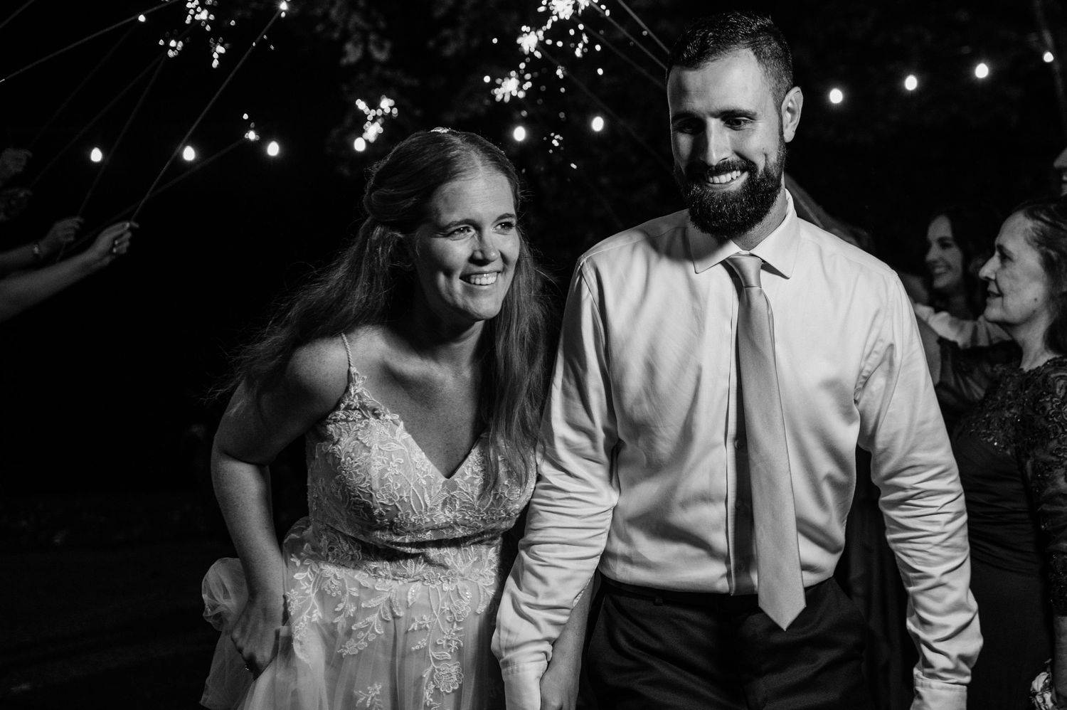 Couple enjoying an outdoor evening celebration under string lights.