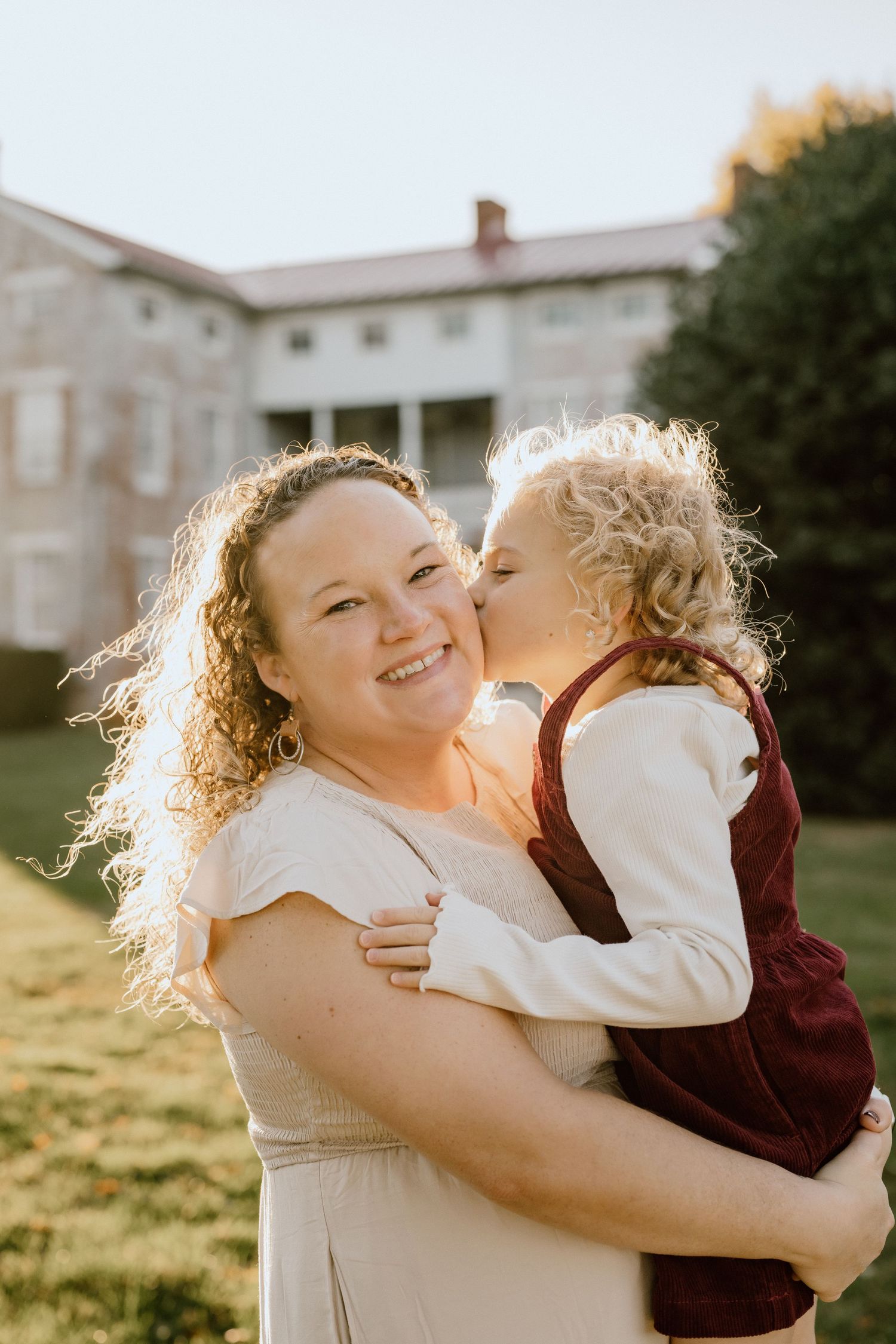 A heartwarming sunset portrait shows tender affection and joy in a backlit outdoor setting.