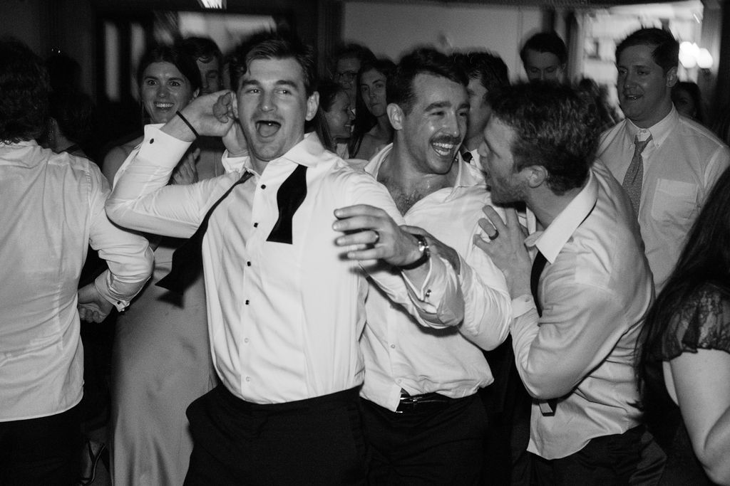 Lively dance party with guests in formal attire celebrating at a wedding reception.