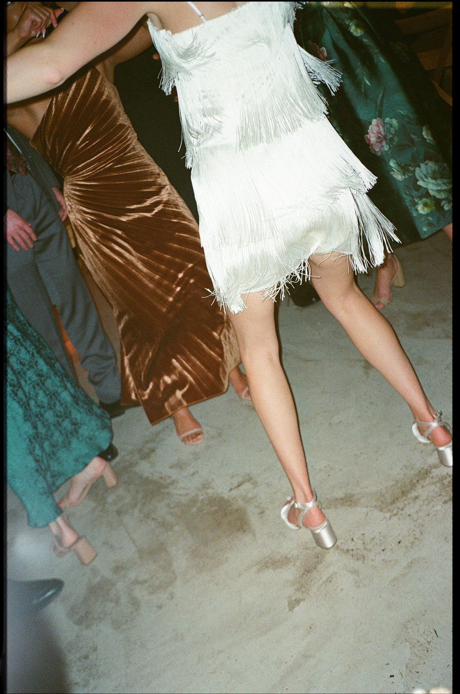 White fringe flapper-style dress and brown velvet dress swish on the dance floor with silver heels.
