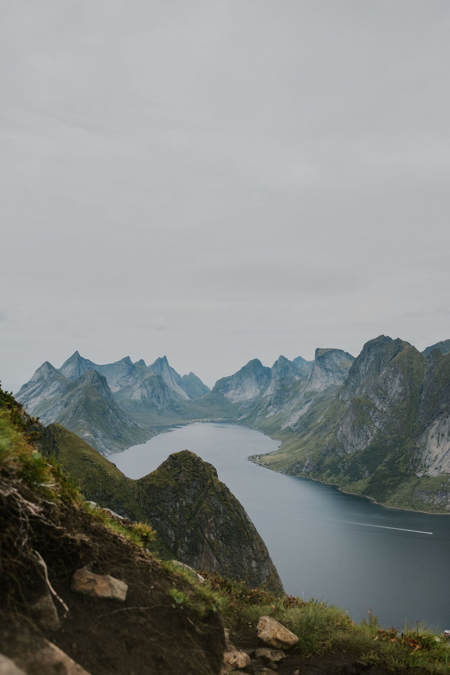 Breathtaking view of a Norwegian fjord surrounded by jagged mountain peaks under cloudy skies.
