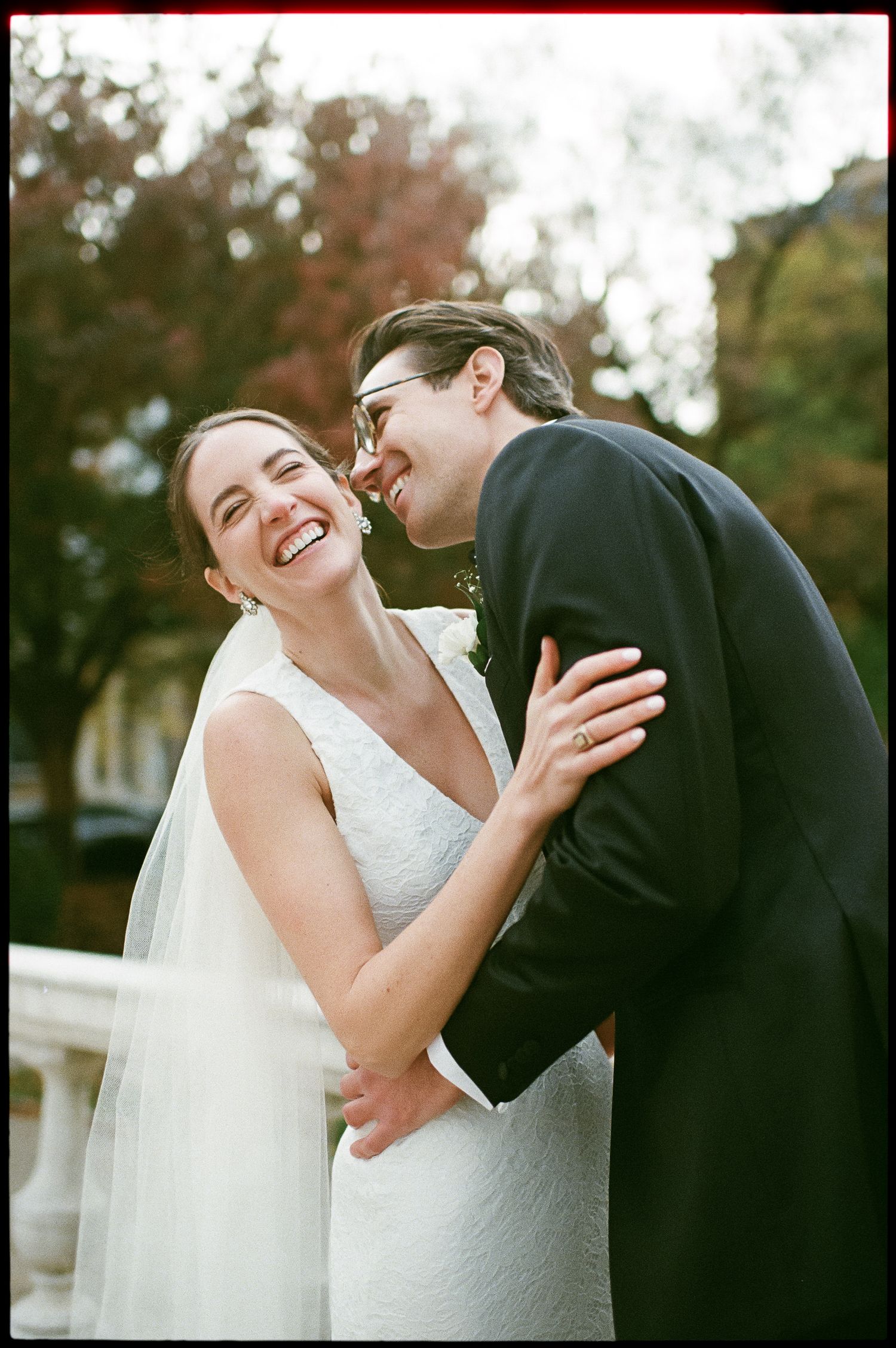 Romantic wedding moment captured during autumn with fall foliage in background.