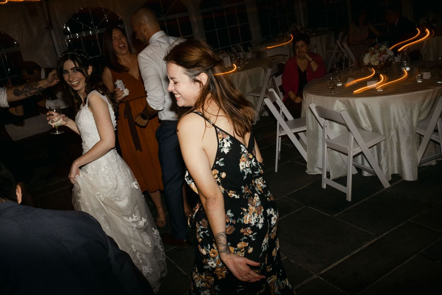 Wedding guests dancing and celebrating on the dance floor under string lights.