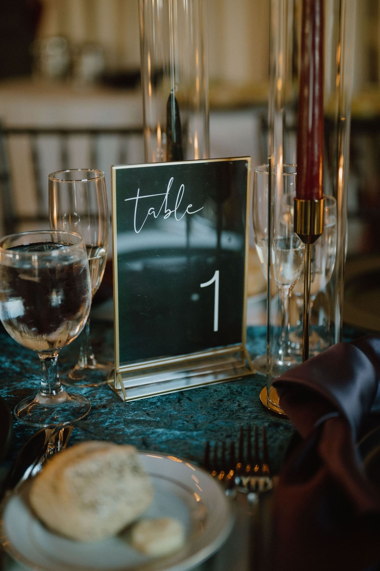 Elegant table setting with a modern calligraphy Table 1 sign and wine glasses.