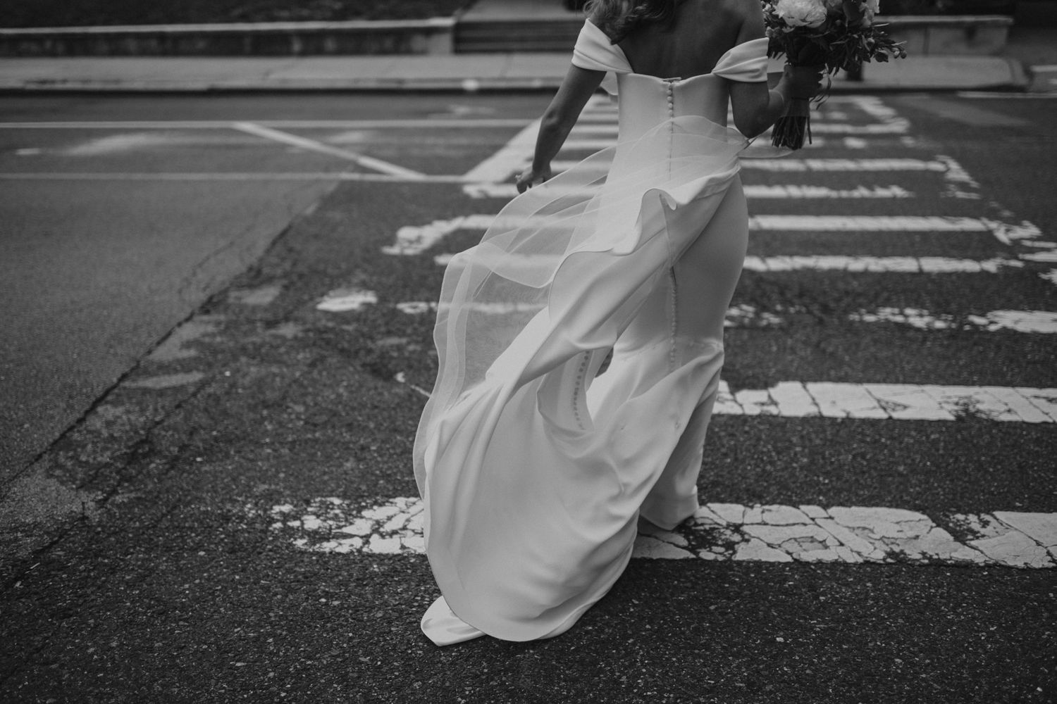 wind blowing wedding dress as bride crosses street in baltimore