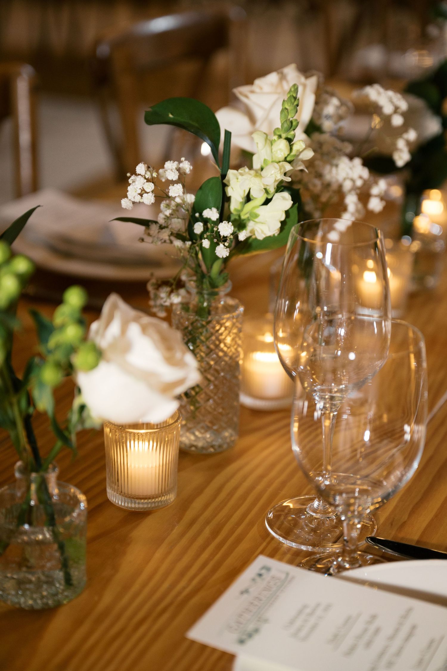 Elegant table setting with white flowers, baby's breath, and glowing candles in glass votives.