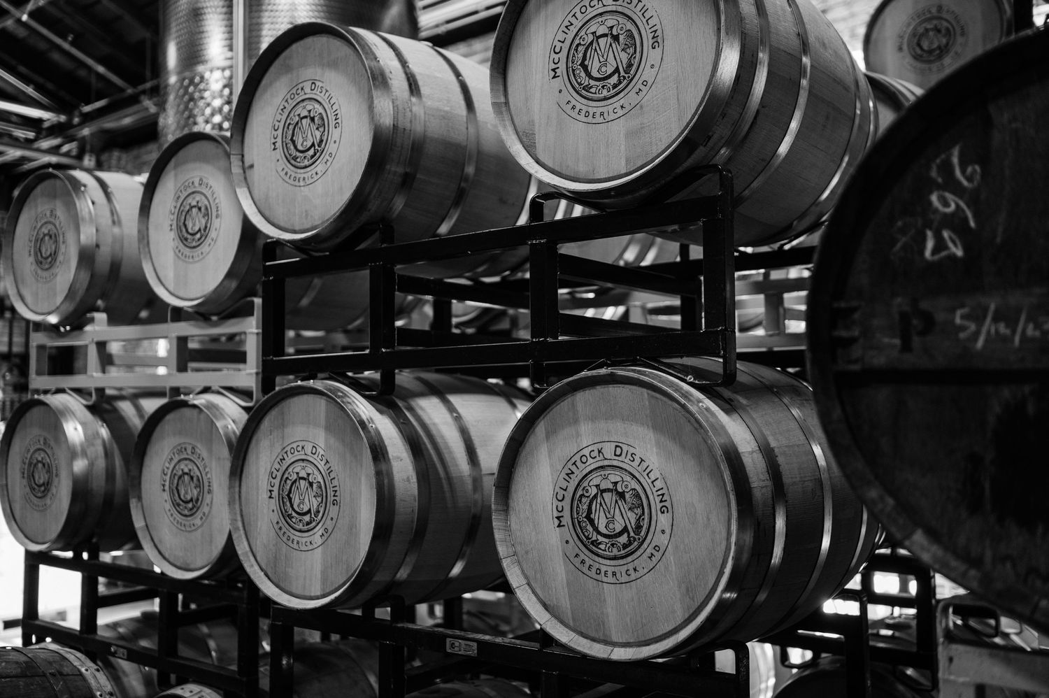 Stacked wooden whiskey barrels in black and white showing distillery aging process.