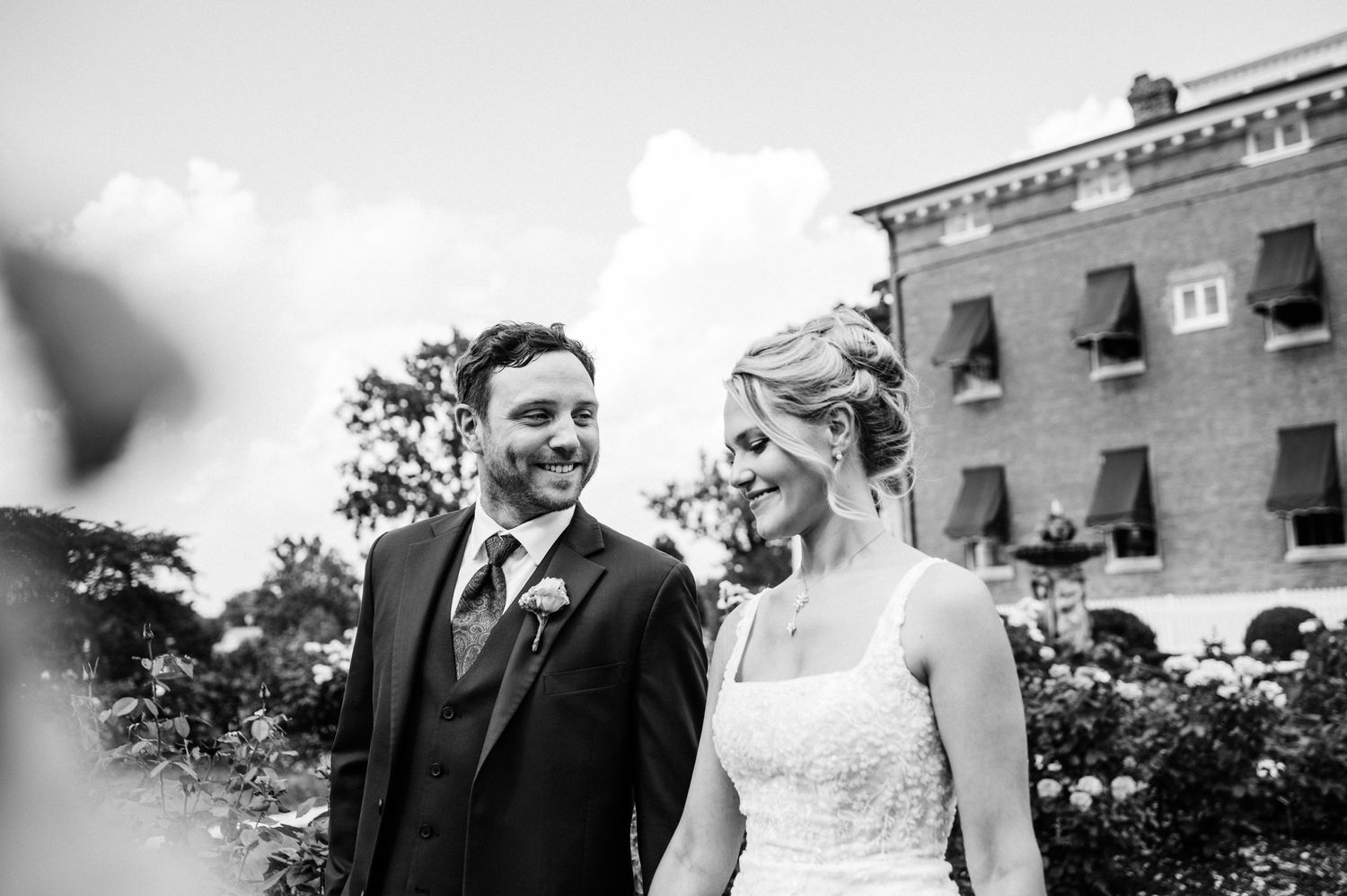 A candid black and white wedding portrait in front of a historic brick building.