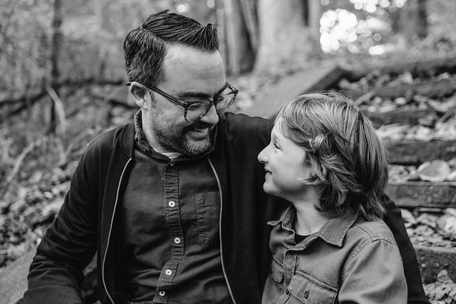 A heartwarming black and white moment between parent and child sitting together outdoors in autumn.