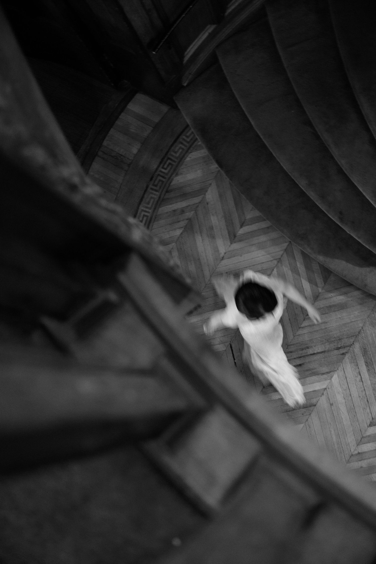 An artistic black and white aerial view of a figure in white on a geometric patterned wooden floor at a Baltimore engineers club wedding