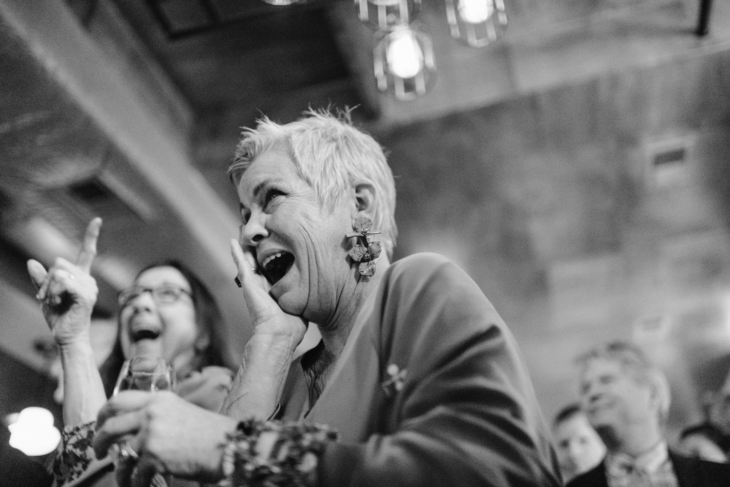 Black and white photo of wedding guests dancing and celebrating with enthusiastic expressions.