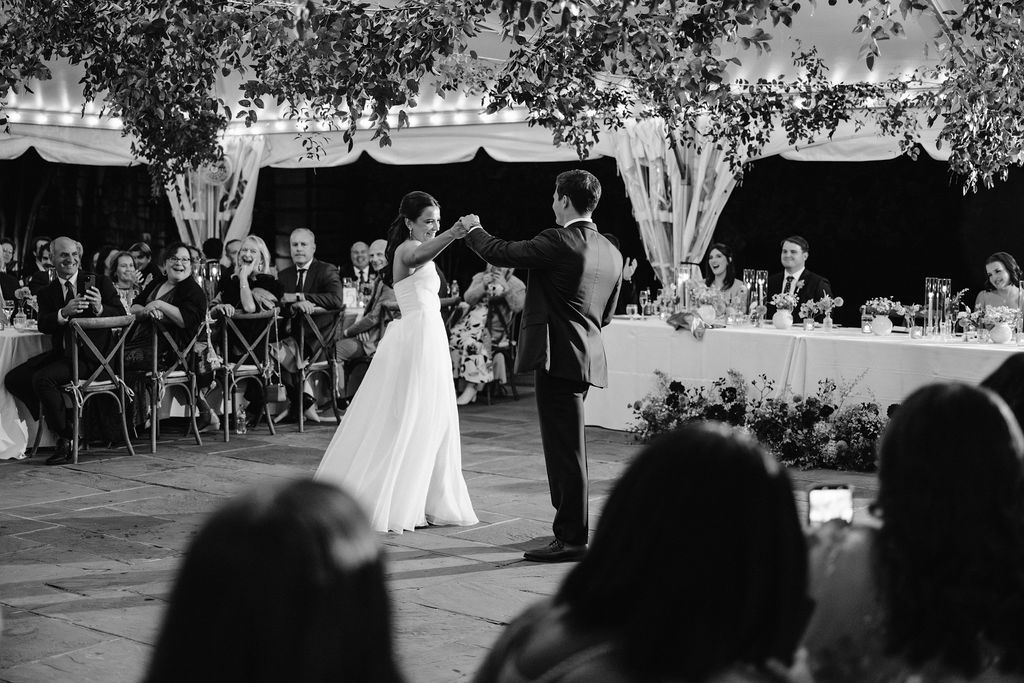 Black and white photo of an outdoor wedding ceremony under trees with string lights at Strong Mansion on Sugarloaf Mountain