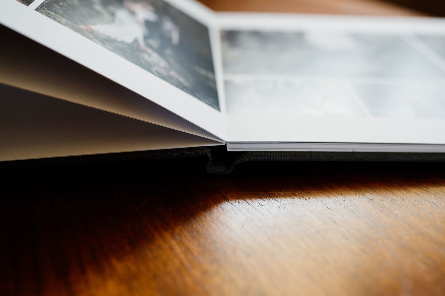 Close-up of white wedding album pages with minimalist design on wooden surface.