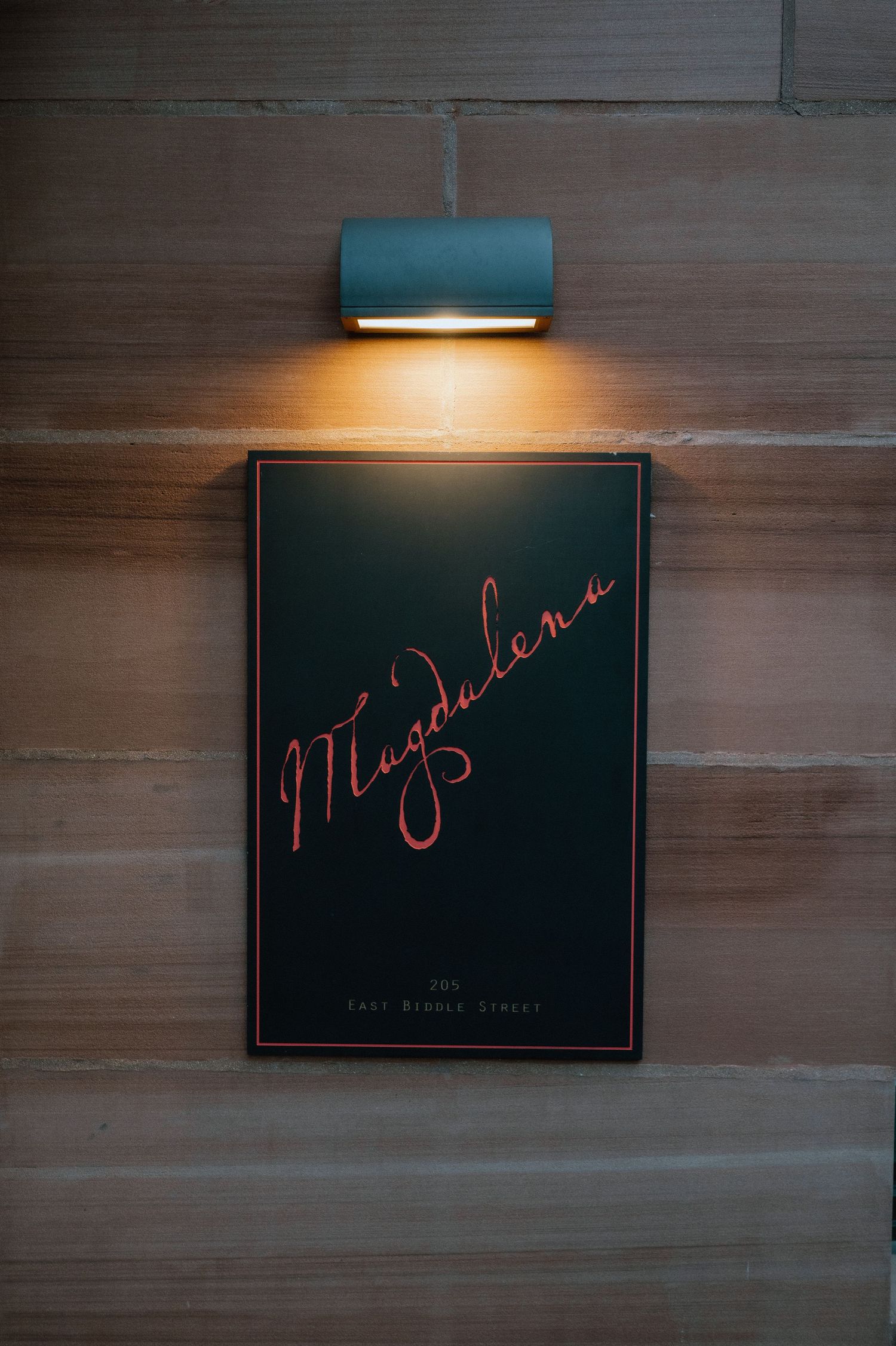 Illuminated wall art display with cursive text under modern sconce lighting.