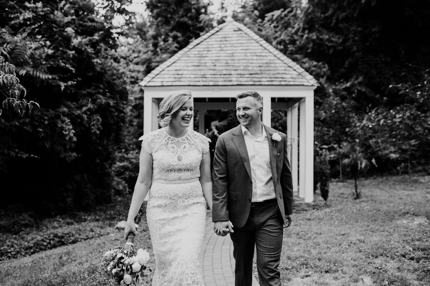 A black and white wedding photo in front of a small white chapel building.