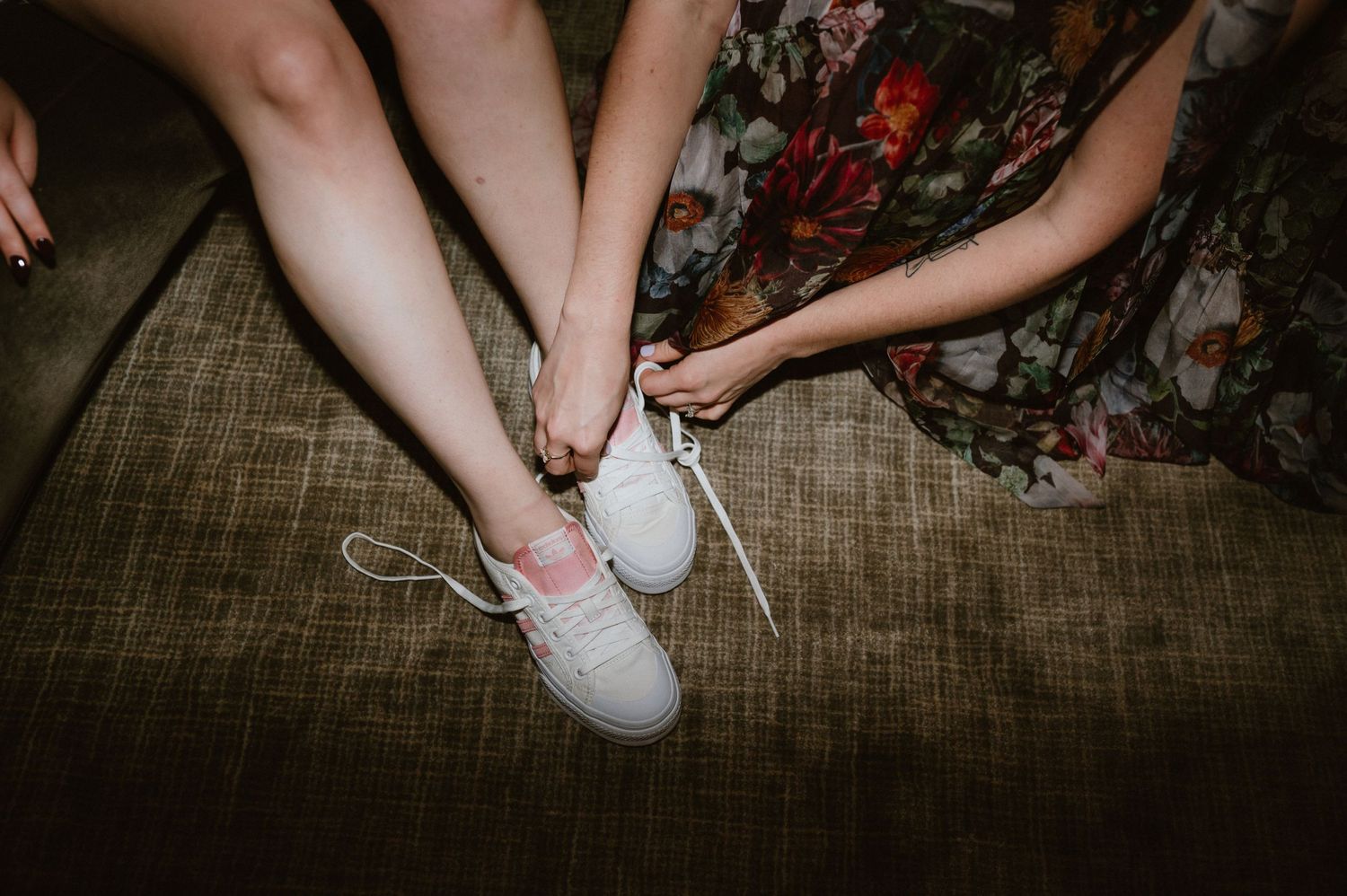 Close-up view of someone putting on white sneakers while sitting on a textured couch.