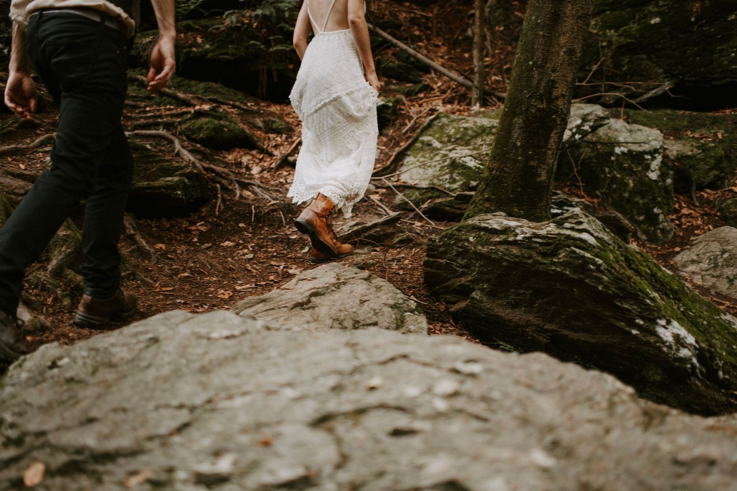 A couple exploring rocky terrain in a forest setting.