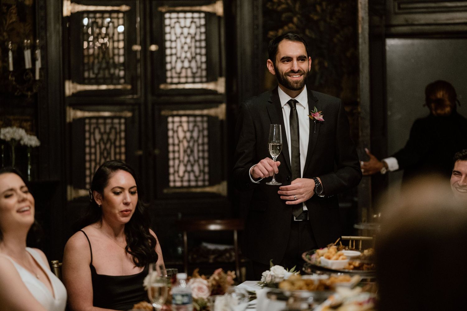 Wedding reception toast at an elegant venue with decorative glass panels and dining tables.