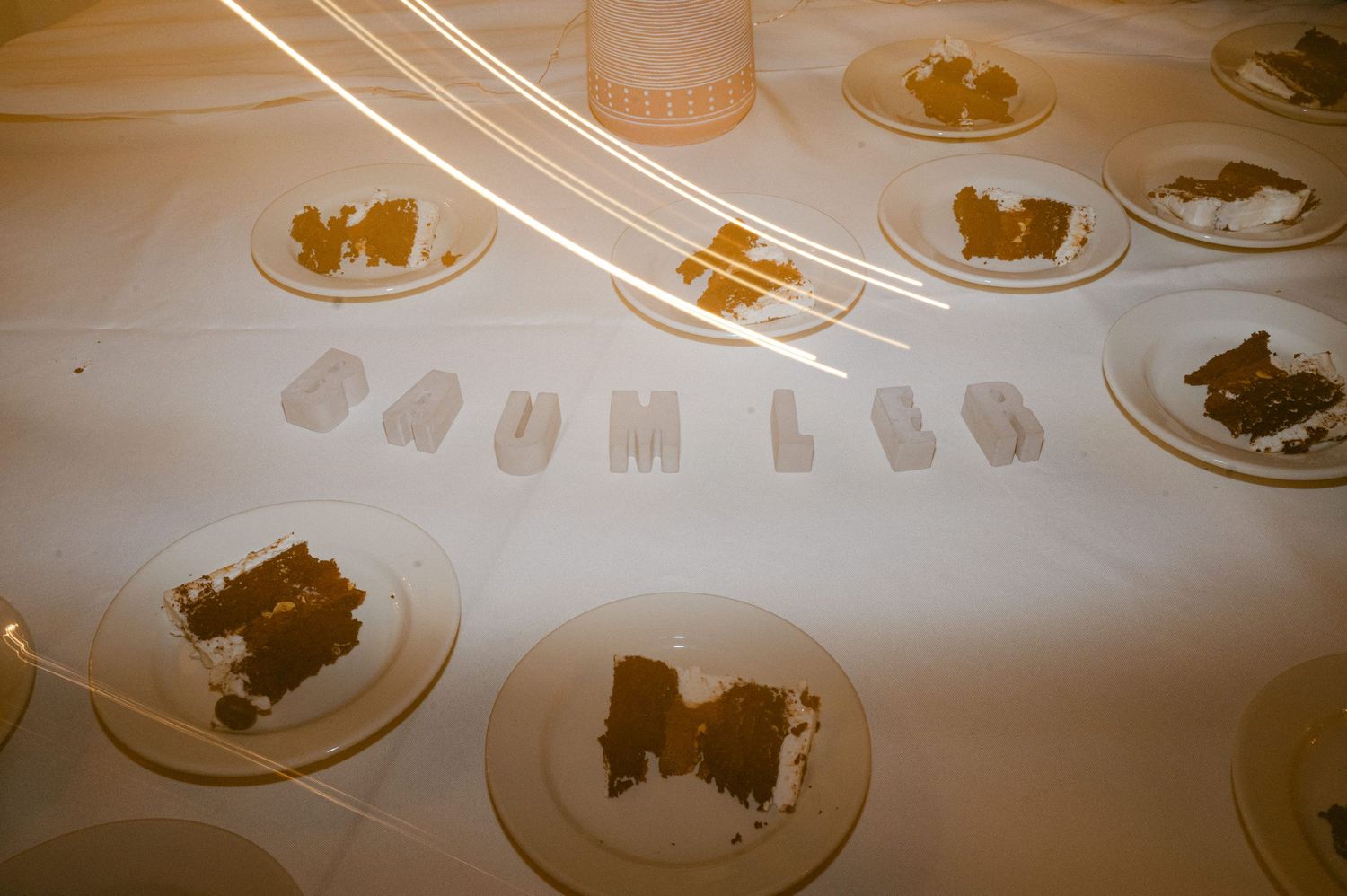 Wedding reception table setting with crumbs scattered on white plates.