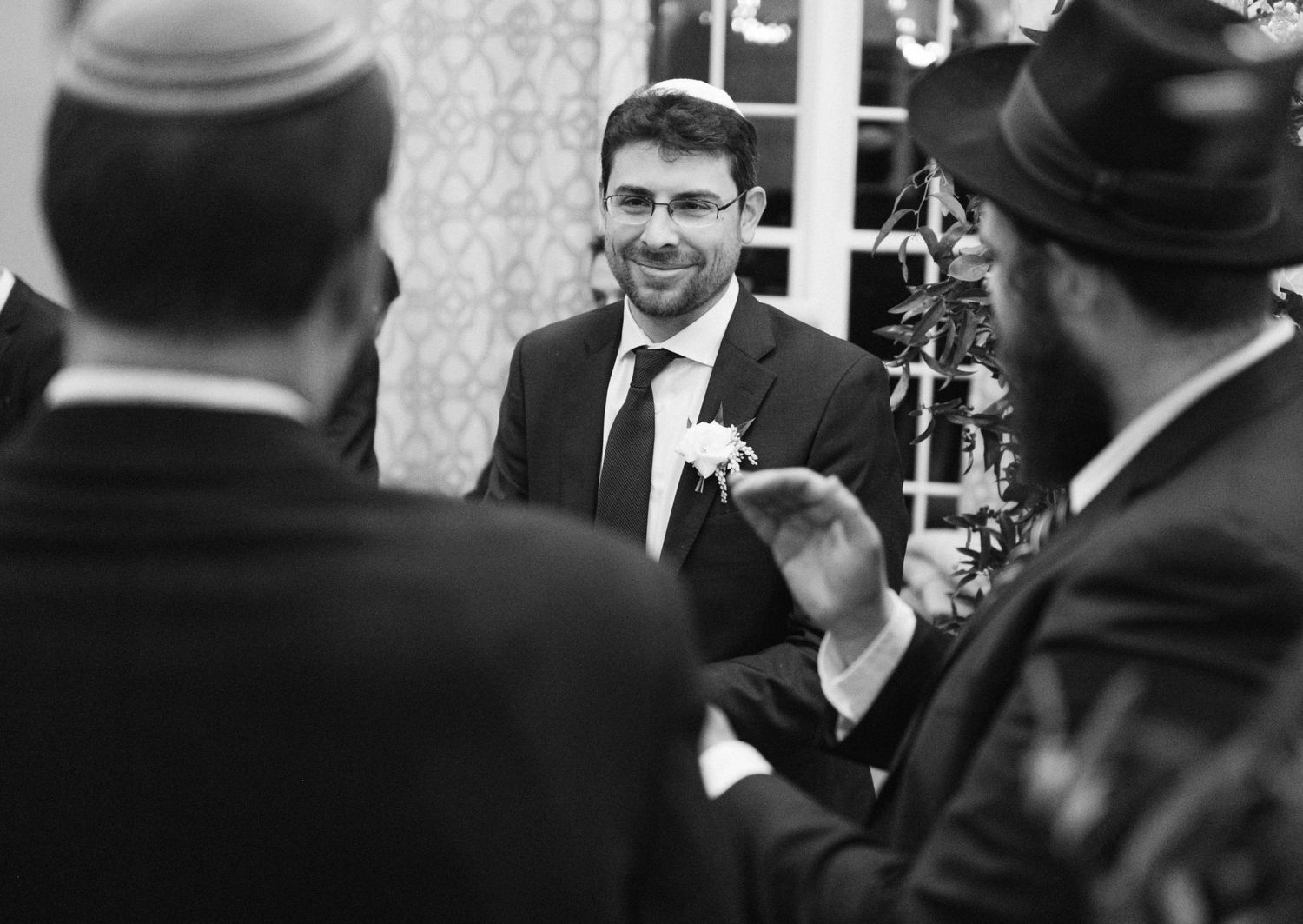 Black and white photo of guests in formal wear having an animated conversation.