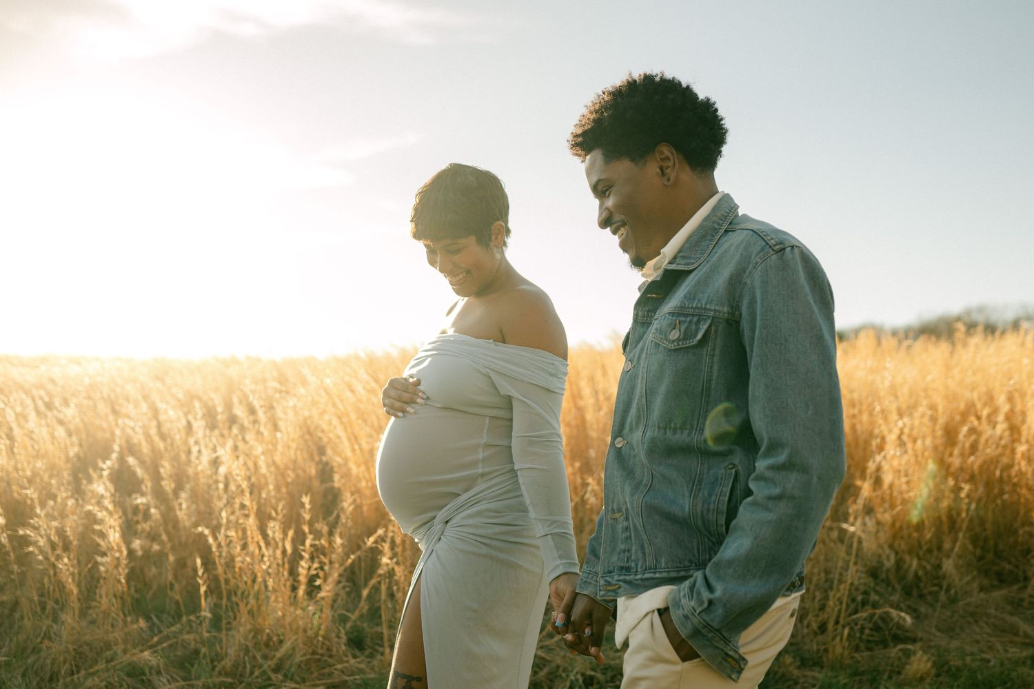 pregnant couple walks together in field in maryland