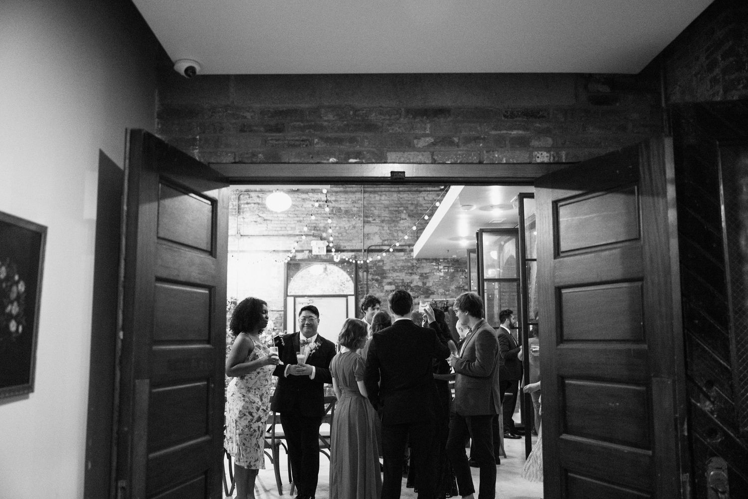 Wedding guests gather in a doorway of a historic building during a celebration.