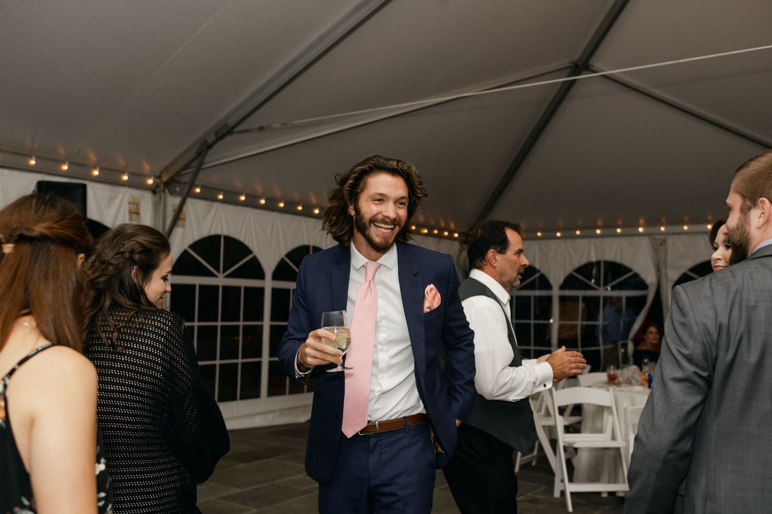Wedding guests socializing and mingling during cocktail hour under a tented reception.