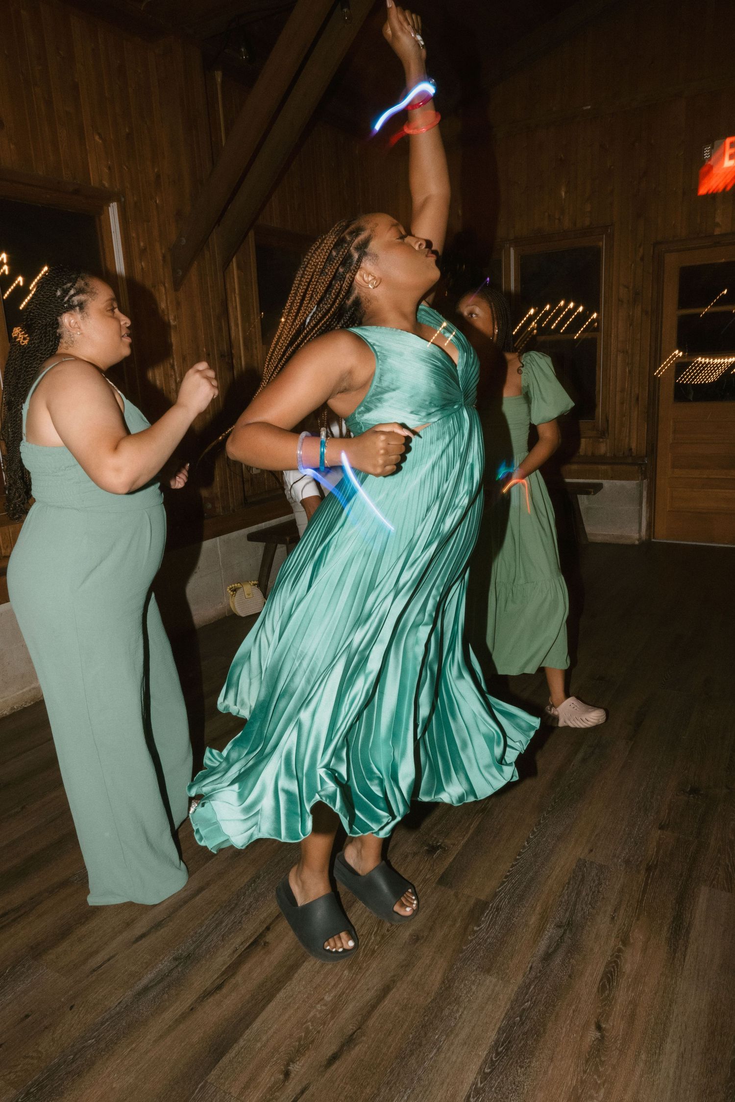 Wedding guests in mint green dresses dancing joyfully at a reception.