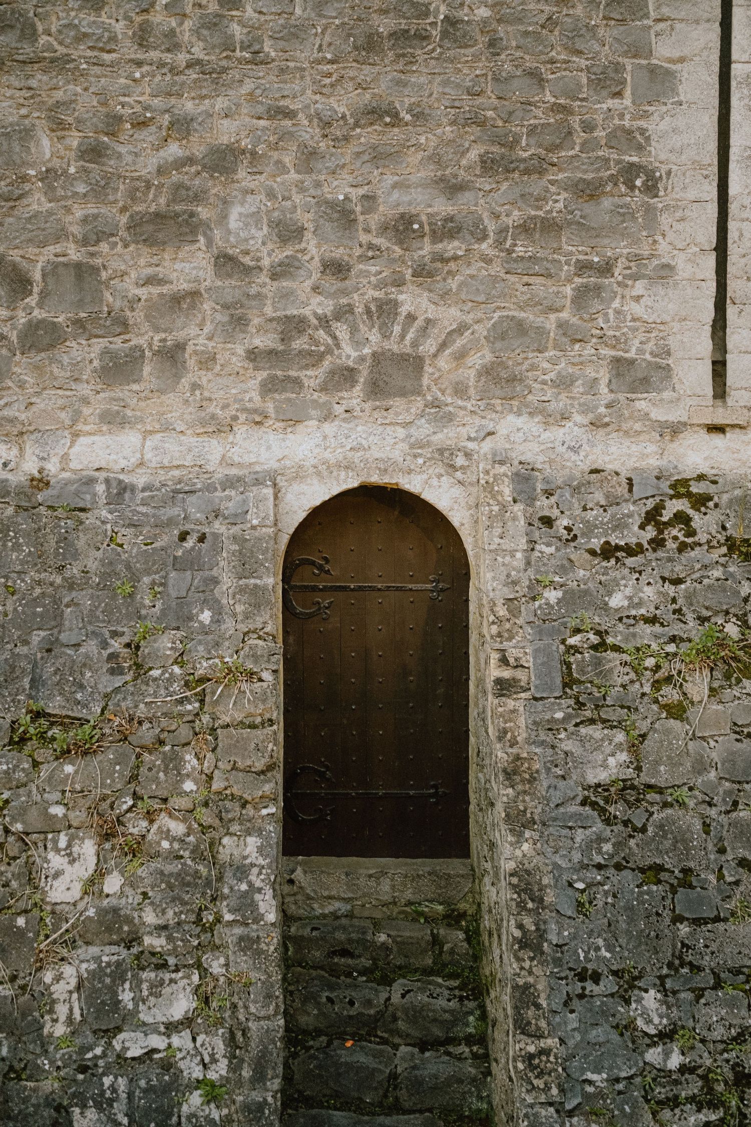 Ancient wooden door set in weathered stone wall with arched entrance.