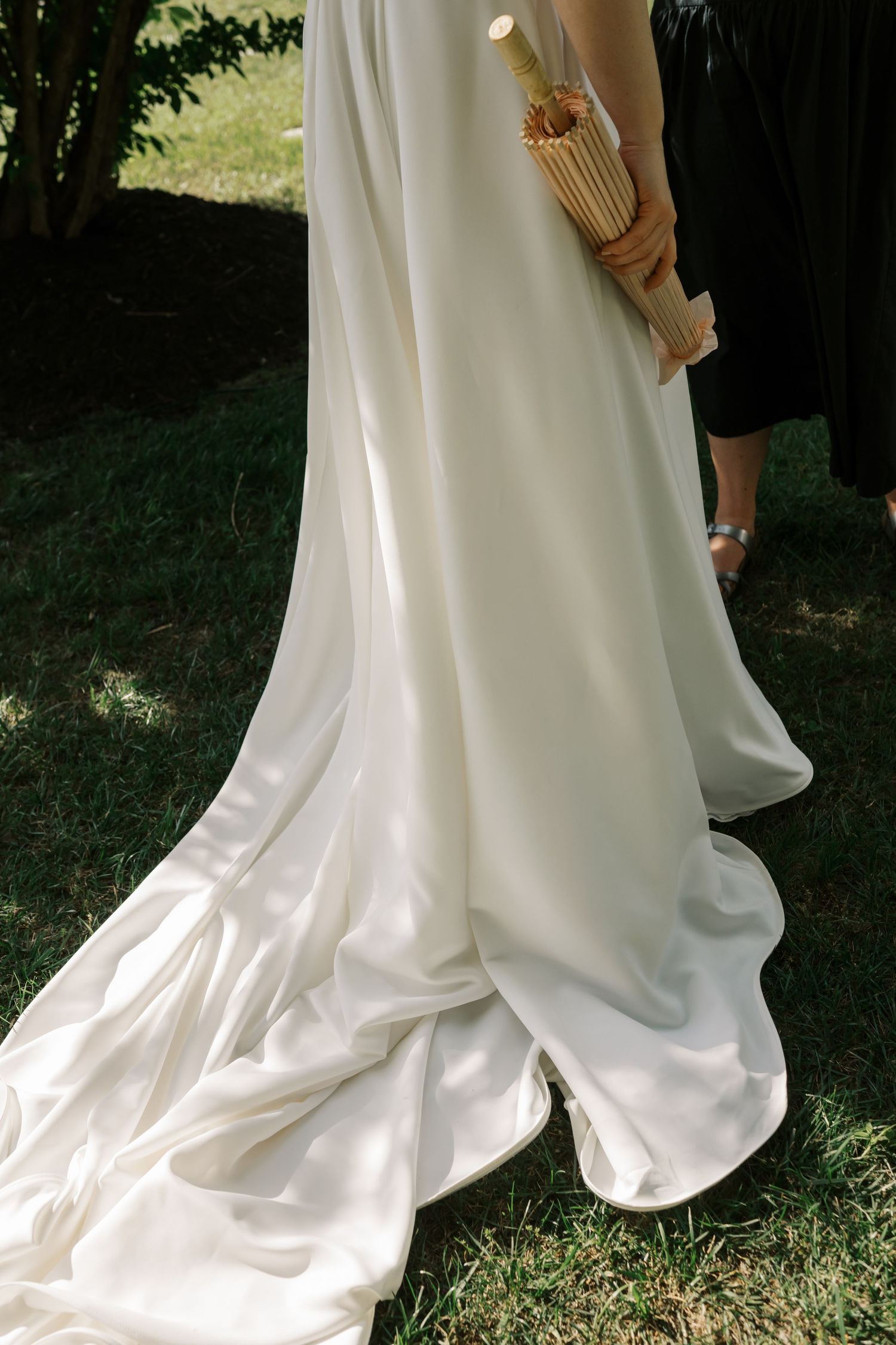Elegant white wedding dress train flowing over green grass.