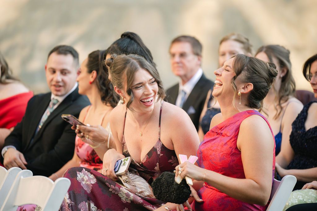 Wedding guests share laughter and smiles during a candid moment at a reception celebration.