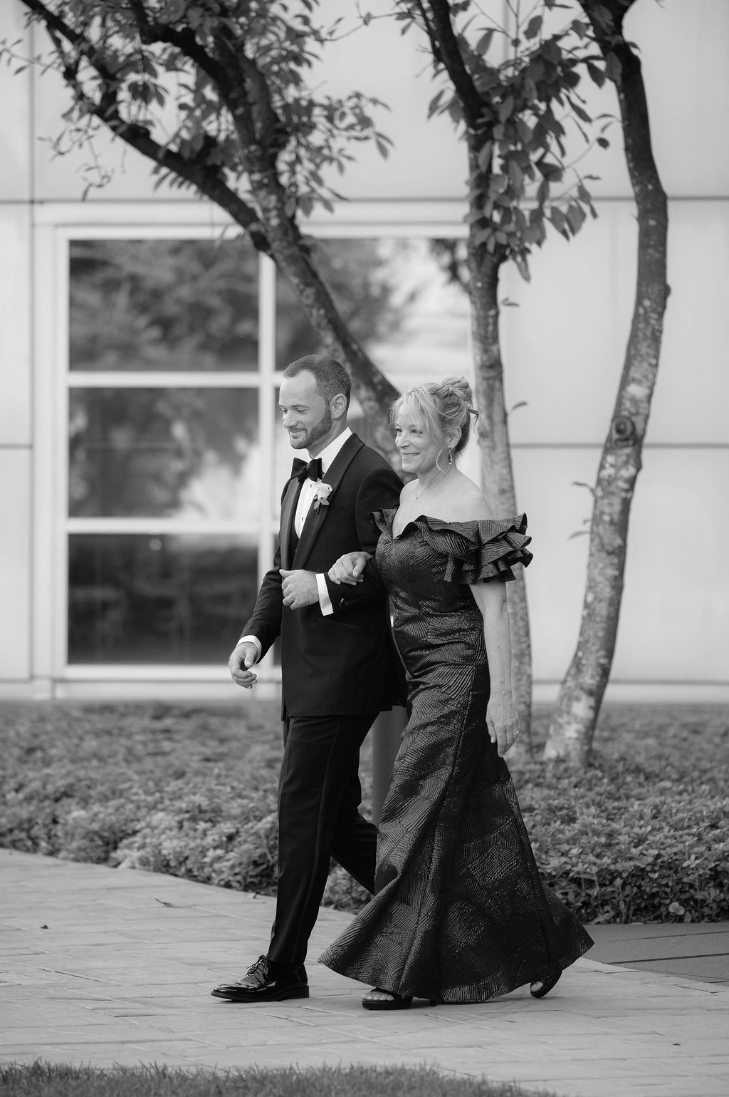 A black and white photo sequence shows a young boy in a suit and an elderly woman in a dress dancing together outdoors.