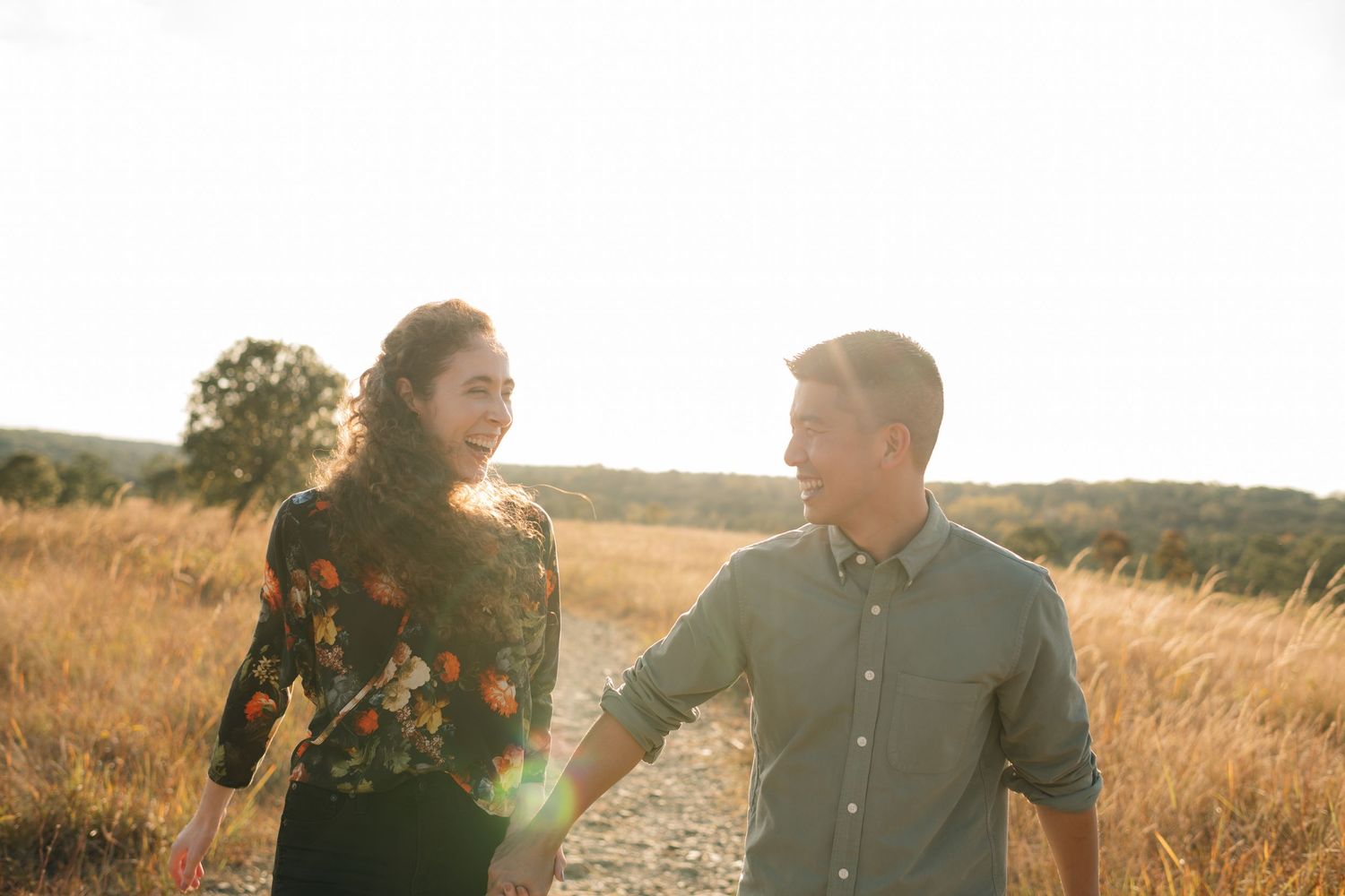 A couple sharing a laugh together in a sun-drenched field.