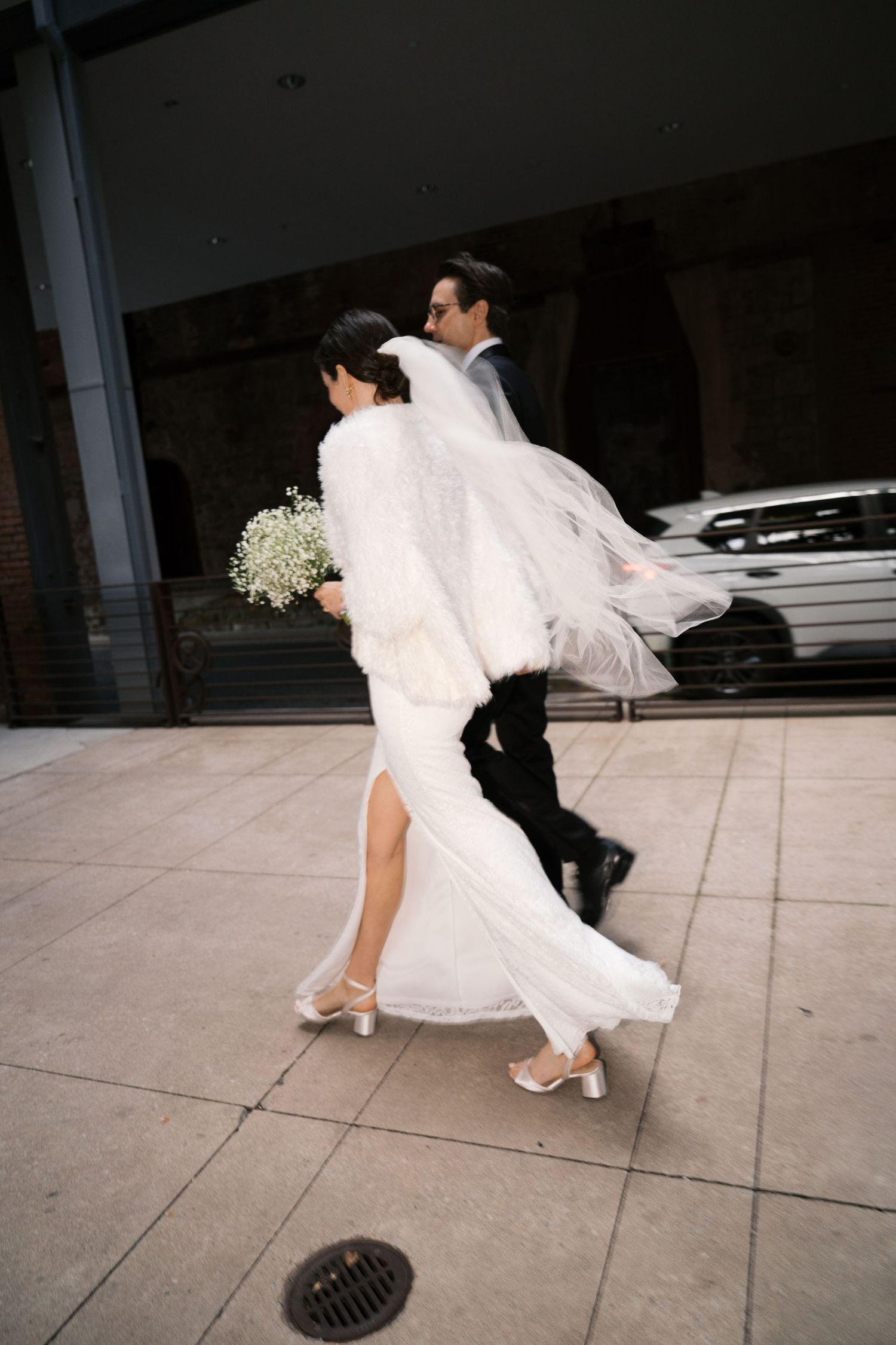 Dynamic shot of couple walking with flowing veil and dress in motion.