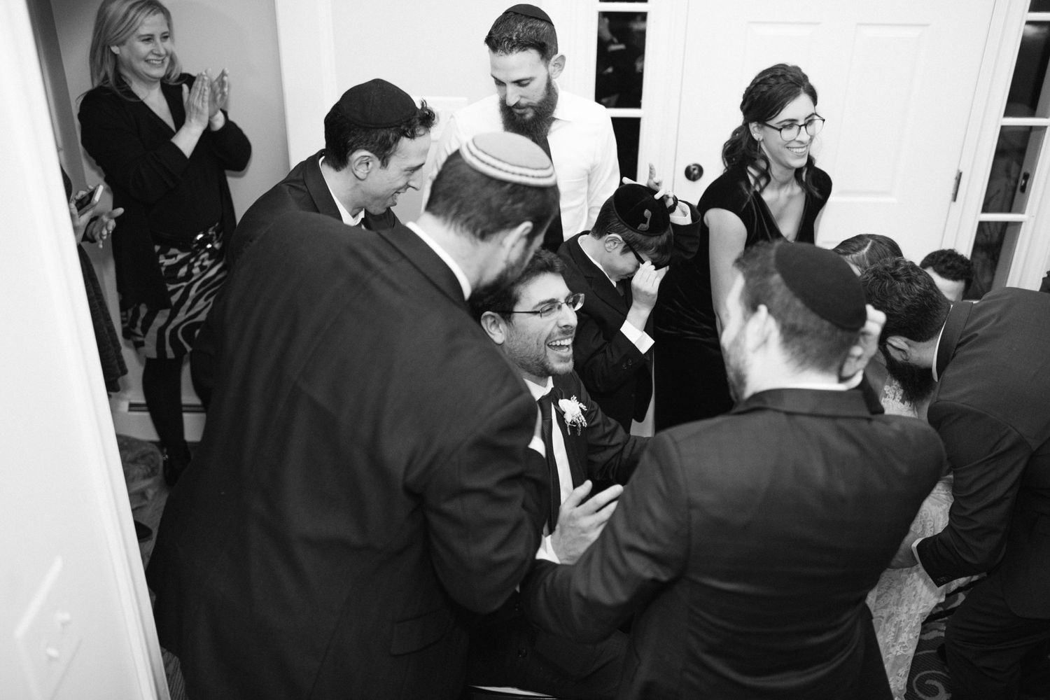 Black and white photo of lively celebration at indoor wedding reception.
