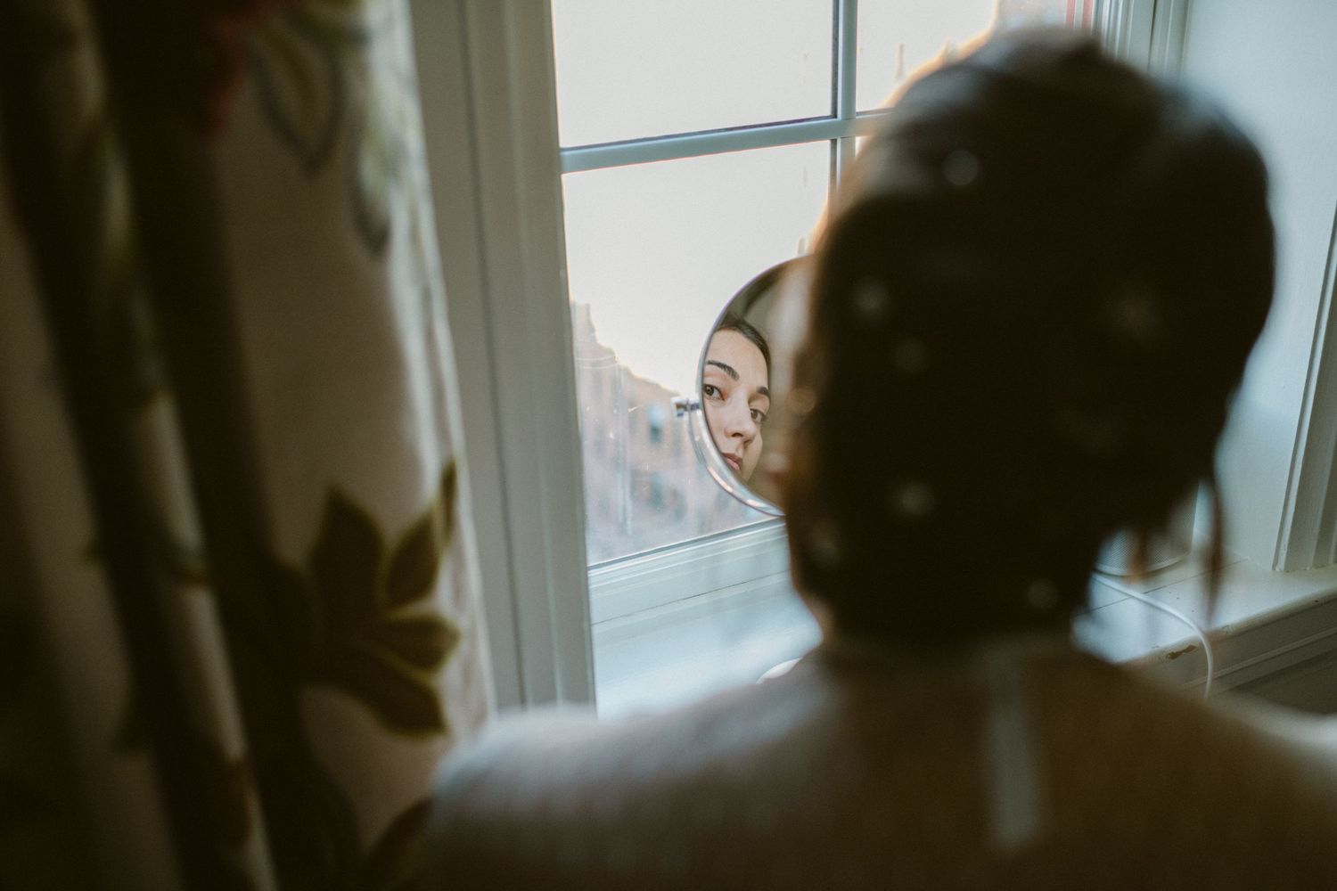 Intimate moment captured through window during wedding preparation.