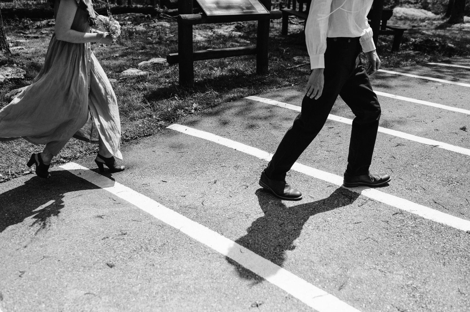 Black and white photo of people dancing on a paved surface with shadows.