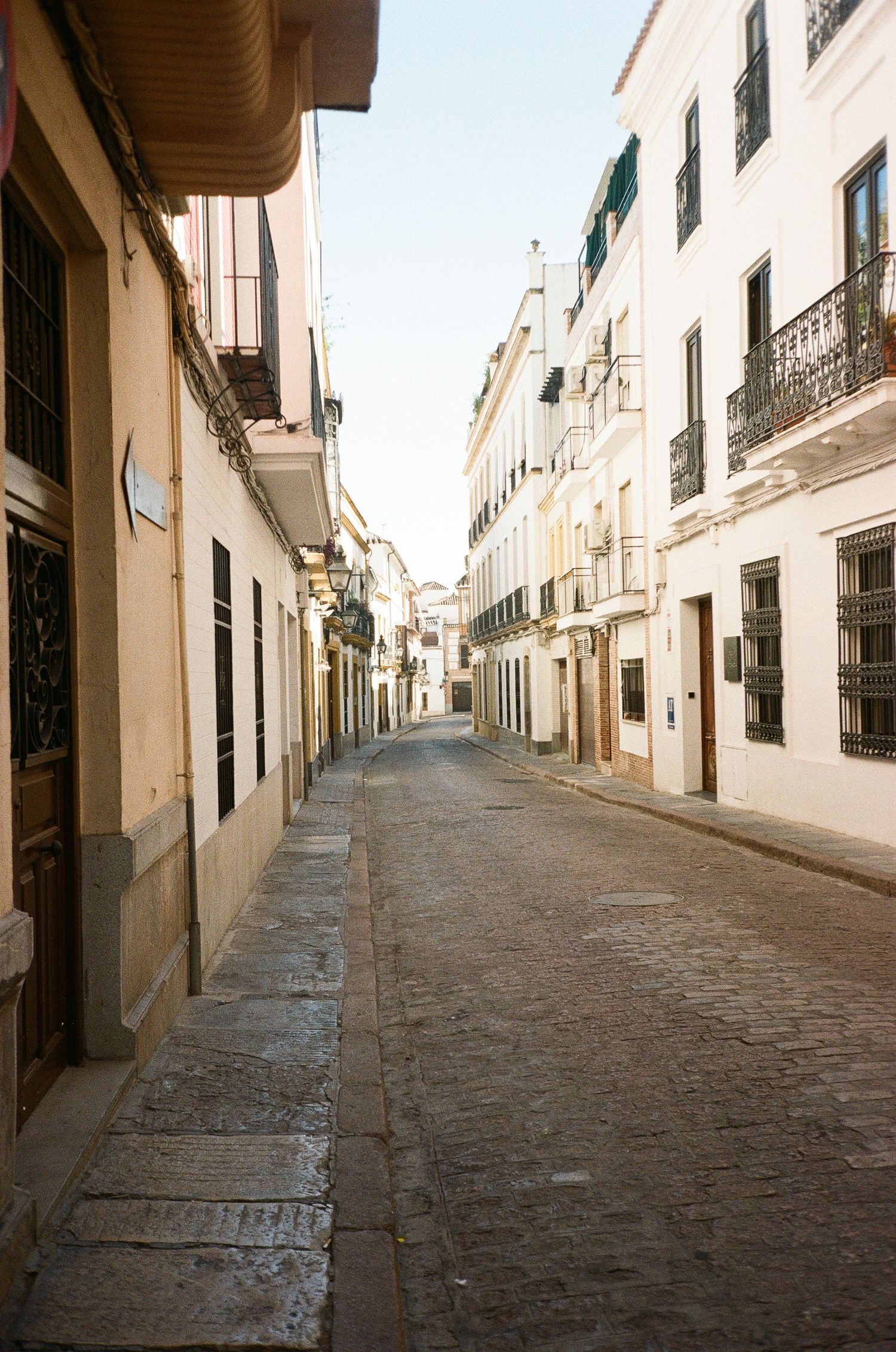 A narrow cobblestone street lined with white buildings in a Mediterranean town.