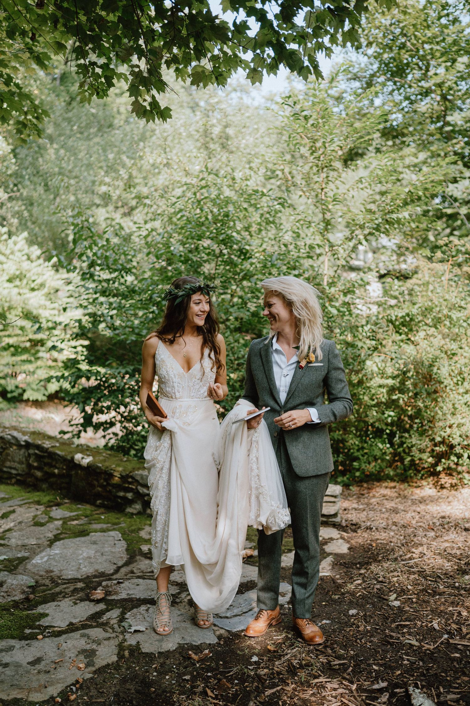 A couple walks together on a stone path through a lush green garden setting.